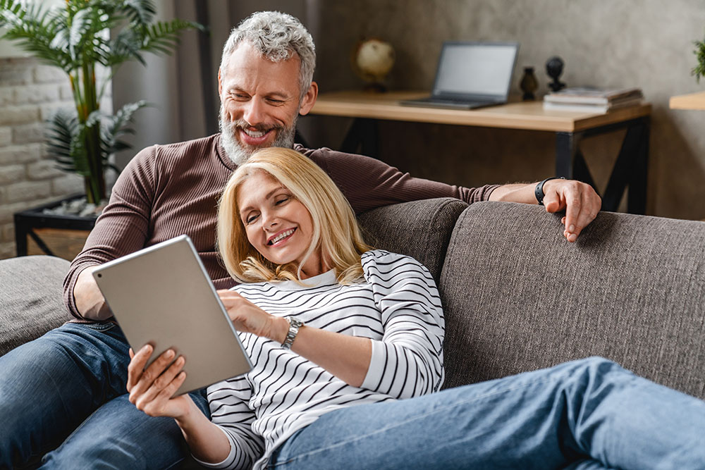 Happy senior couple using digital tablet on sofa